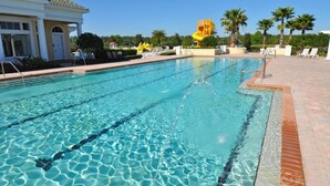 A swimming pool with clear water, surrounded by a brick deck and palm trees. - Providence At Crofton Springs 6 Bedroom Home by RedAwning (Davenport)