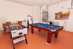 Une pièce équipée d’un baby-foot, d’une table de billard et d’un petit coin repas.