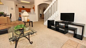 A living room with a glass coffee table, a sofa, a TV stand, and a staircase leading to a kitchen. - 684od 5 Bedroom Home by RedAwning (Davenport)