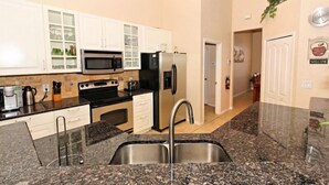 A modern kitchen with granite countertops, stainless steel appliances, and white cabinetry. - 351bs 5 Bedroom Villa by RedAwning (Davenport)