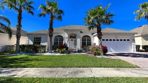 A two-story house with a front entrance, a garage, and palm trees. - 351bs 5 Bedroom Villa by RedAwning (Davenport)