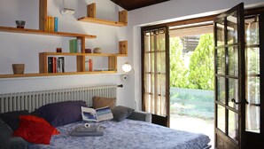 A bedroom with a bed, a bookshelf, a window, and a door.