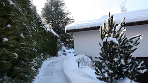 A snow-covered pathway leading to a building with a snow-covered roof.