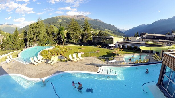 A pool area with multiple swimming pools, lounge chairs, and a view of mountains in the background.