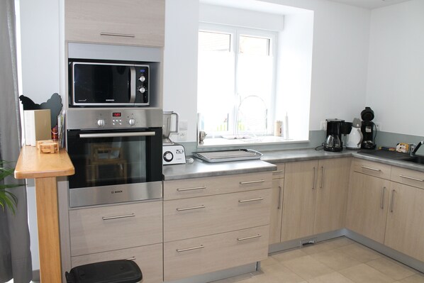 A modern kitchen with stainless steel appliances, wooden cabinets, and a window providing natural light.