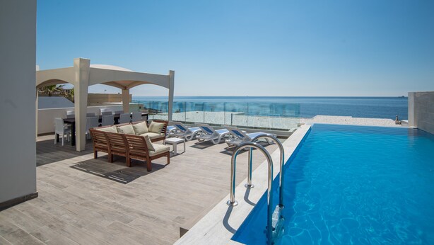 A rooftop pool area with lounge chairs and a view of the ocean.