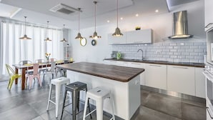 A modern kitchen with a central island, pendant lights, and a white backsplash. - Villa La Perla - beachfront villa for ten, private pool and amazing views by MyWaycation (Rogoznica)