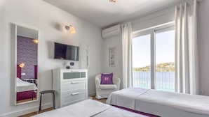 A modern hotel room with two beds, a TV, a desk, and a balcony with a view of the sea. - Villa La Perla - beachfront villa for ten, private pool and amazing views by MyWaycation (Rogoznica)