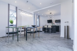 A modern dining area with a glass-top table, metal chairs, and a chandelier.