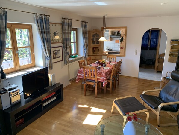 A living room with a TV, wooden dining table, chairs, and a glass coffee table. - Cosy, tasteful, mountain views. ski, hiking trails, golf, restaurants nearby. (Oberstaufen)