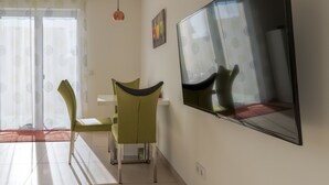 A room with a dining area featuring a table and two chairs, a large mirror on the wall, and a sliding glass door with a patterned curtain. - Modern apartment in a quiet location (Bischberg)