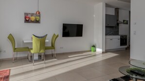 A modern living room with a dining area, a kitchen, and a TV mounted on the wall. - Modern apartment in a quiet location (Bischberg)