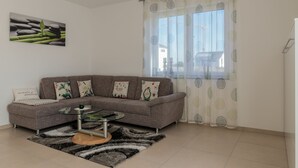 A modern living room with a grey sectional sofa, a glass coffee table, and a patterned rug. - Modern apartment in a quiet location (Bischberg)