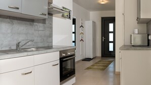 A modern kitchen with white cabinets, a stainless steel sink, and an oven. - Modern apartment in a quiet location (Bischberg)