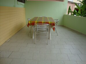 A dining table with a plaid tablecloth, four metal chairs, and a tiled floor.