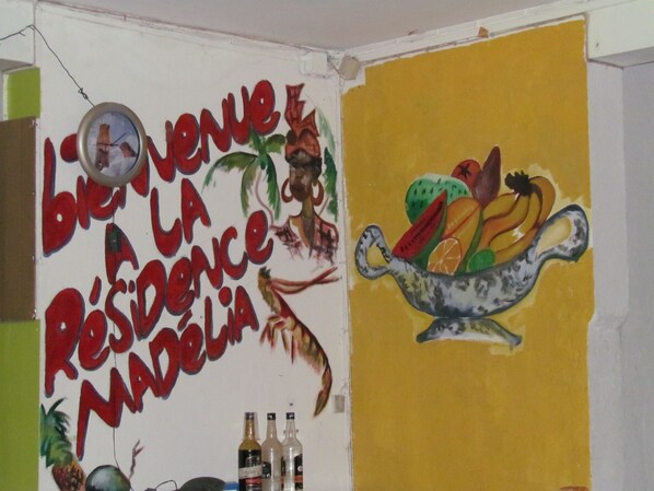 A room with a wall mural featuring a welcome sign and a fruit bowl.