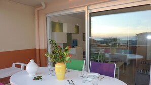 A dining table set with a vase of flowers, a white pitcher, and cutlery. - <--Right on this BEACH, Bright 1-Bedroom Apartment; OCEAN VIEW. ****42 m² + TERRACE + garage + Wi-Fi (Capbreton)