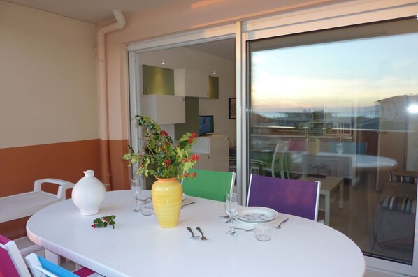 A dining table set with a vase of flowers, a white pitcher, and cutlery. - <--Right on this BEACH, Bright 1-Bedroom Apartment; OCEAN VIEW. ****42 m² + TERRACE + garage + Wi-Fi (Capbreton)
