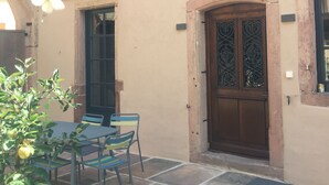 A traditional half-timbered building with a stone patio and outdoor seating. - Superb 18th century farmhouse, in the heart of the vineyard. (Epfig)