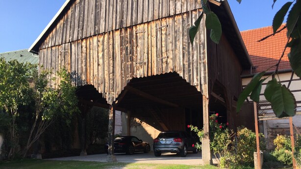 A rustic barn with a covered entrance, a parked car, and surrounding greenery. - Superb 18th century farmhouse, in the heart of the vineyard. (Epfig)