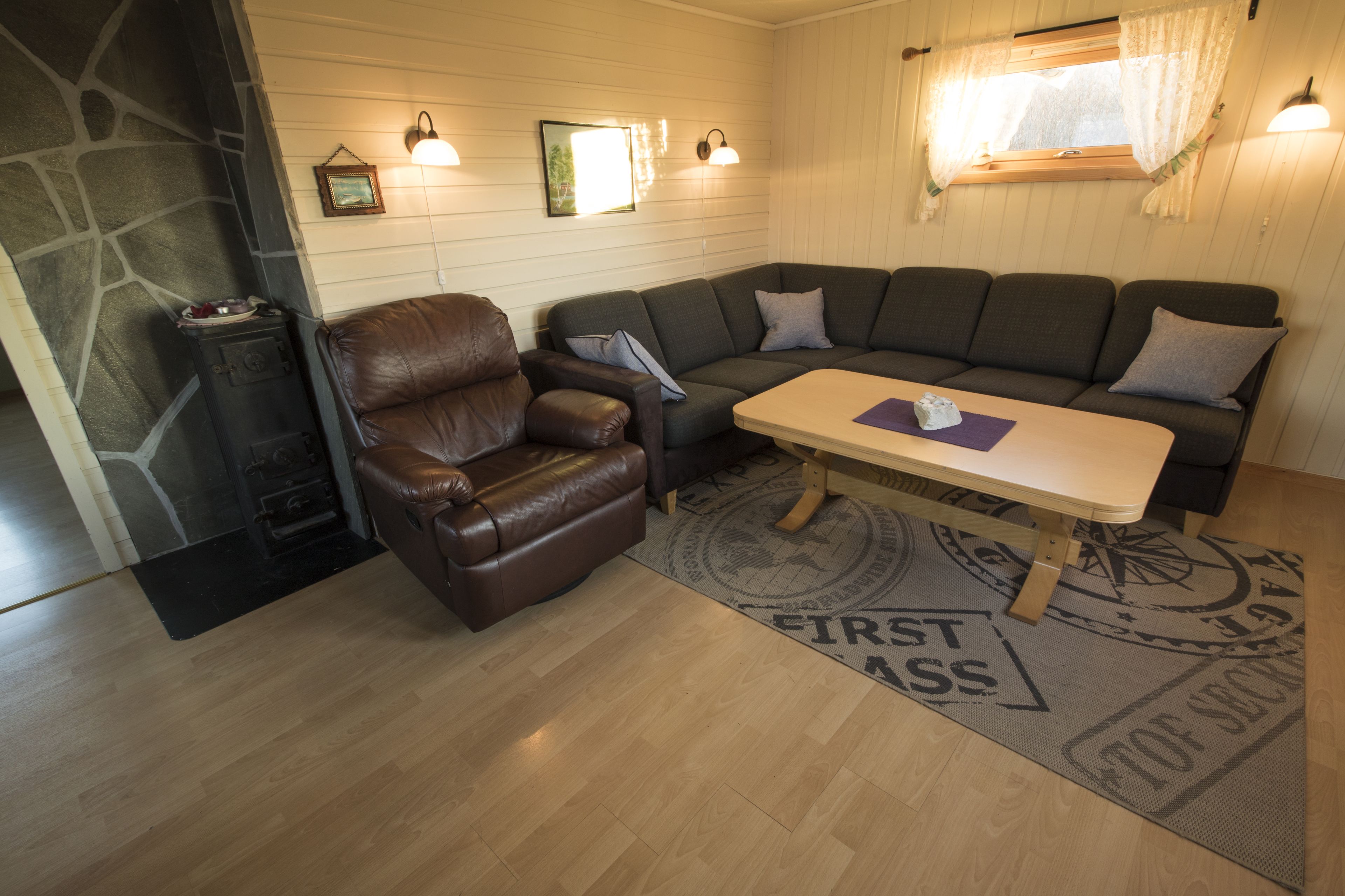 A cozy living area with a brown leather armchair, a dark green sofa, and a wooden coffee table.