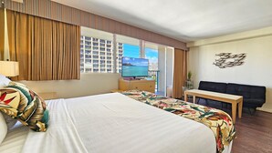 Une chambre d’hôtel avec un lit, un bureau, une télévision et une vue sur la mer.