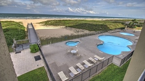 A rooftop pool area with multiple swimming pools, a beach view, and a grassy landscape. - Walls of windows overlooking the blue ocean!  (South Padre Island)