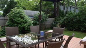 A glass-top table with wicker chairs in a backyard setting. - Falmouth - walk to beach, walking path, close to downtown, private yard (Falmouth)