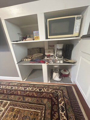 A kitchen area with a microwave, coffee maker, and various kitchen utensils.