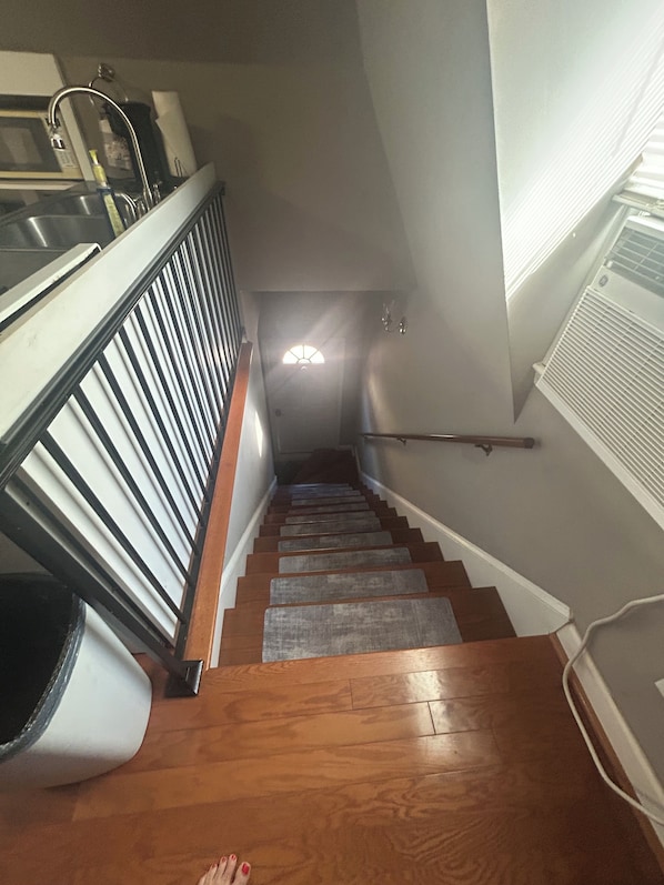 A wooden staircase with a handrail, leading to a landing with a light fixture.