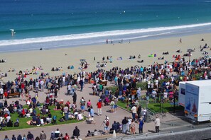 A crowded beach with people sitting and walking.
