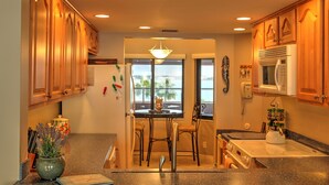A kitchen with wooden cabinets, a dining table with chairs, a stove, and a view through the window.