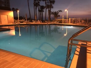 Relax by the pool surrounded by palm trees and a clear sky.