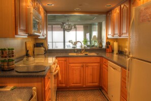Kitchen features a dishwasher, stainless steel sink, and a small island with a kettle and cutting board.