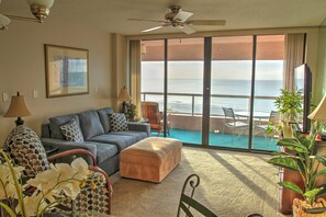 Relax in this stylish living room with a sofa, ottoman, and ocean views from the balcony.