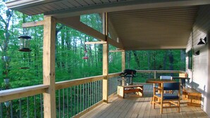 A wooden deck with a table and chairs, surrounded by a railing, overlooking a forested area. - Private & unplugged.  Near Fallingwater, GAP and Ohiopyle. 5-star reviews (Fort Hill)