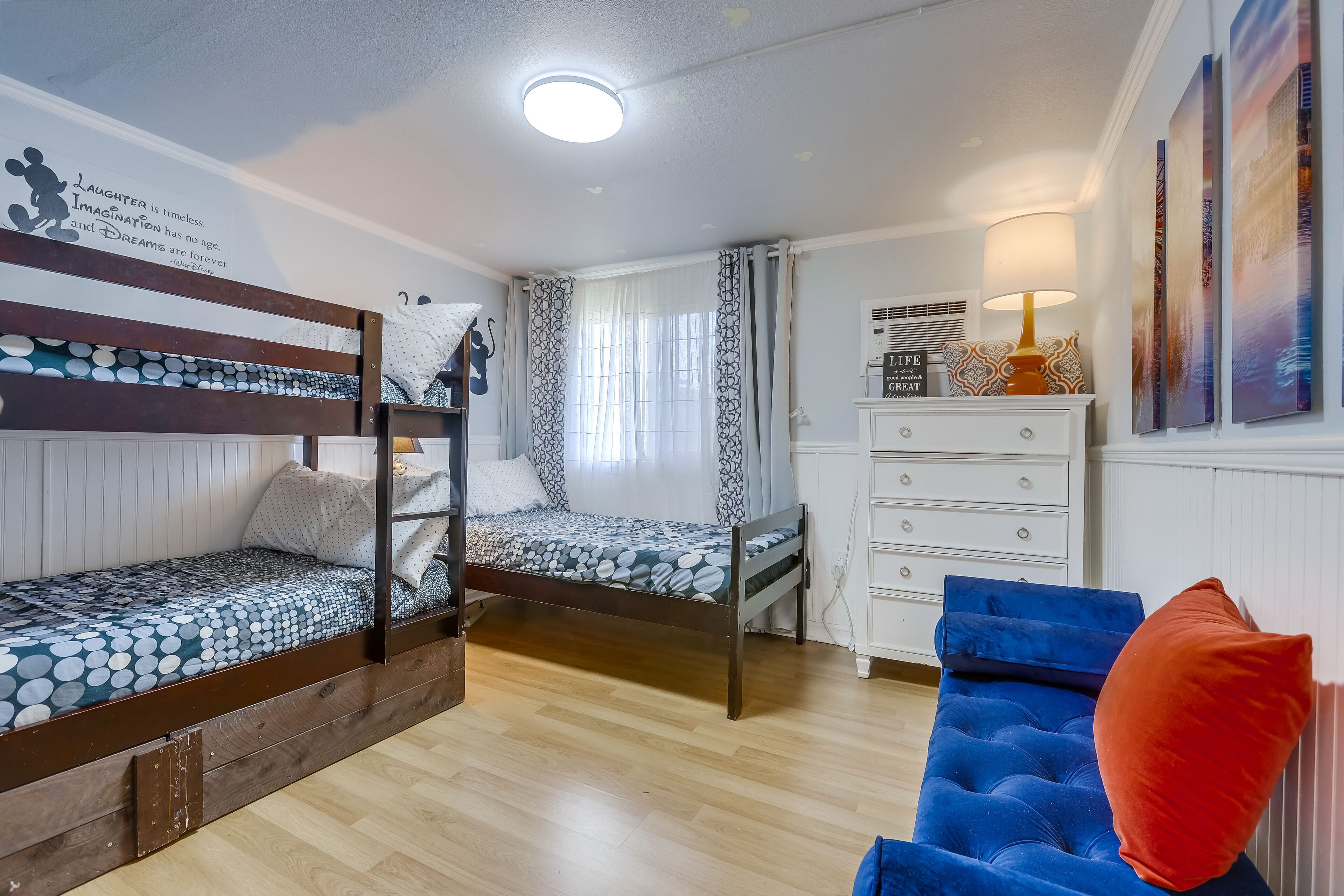Ein Zimmer mit Etagenbetten, einem Schminktisch, einem Stuhl und einer Wand mit motivierenden Sprüchen.