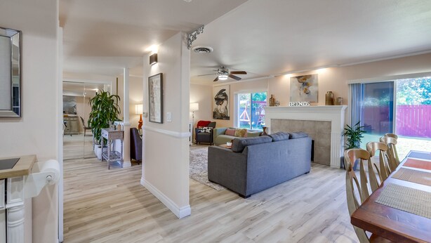 Ein geräumiger Wohnbereich mit grauem Sofa, einem Holzesstisch und einem Deckenventilator.