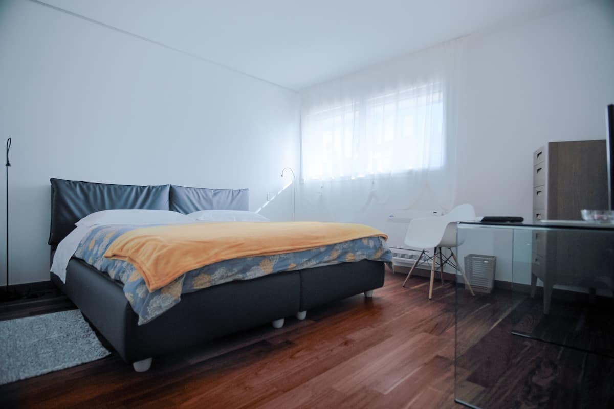 Een moderne slaapkamer met een bed, een bureau en een stoel.