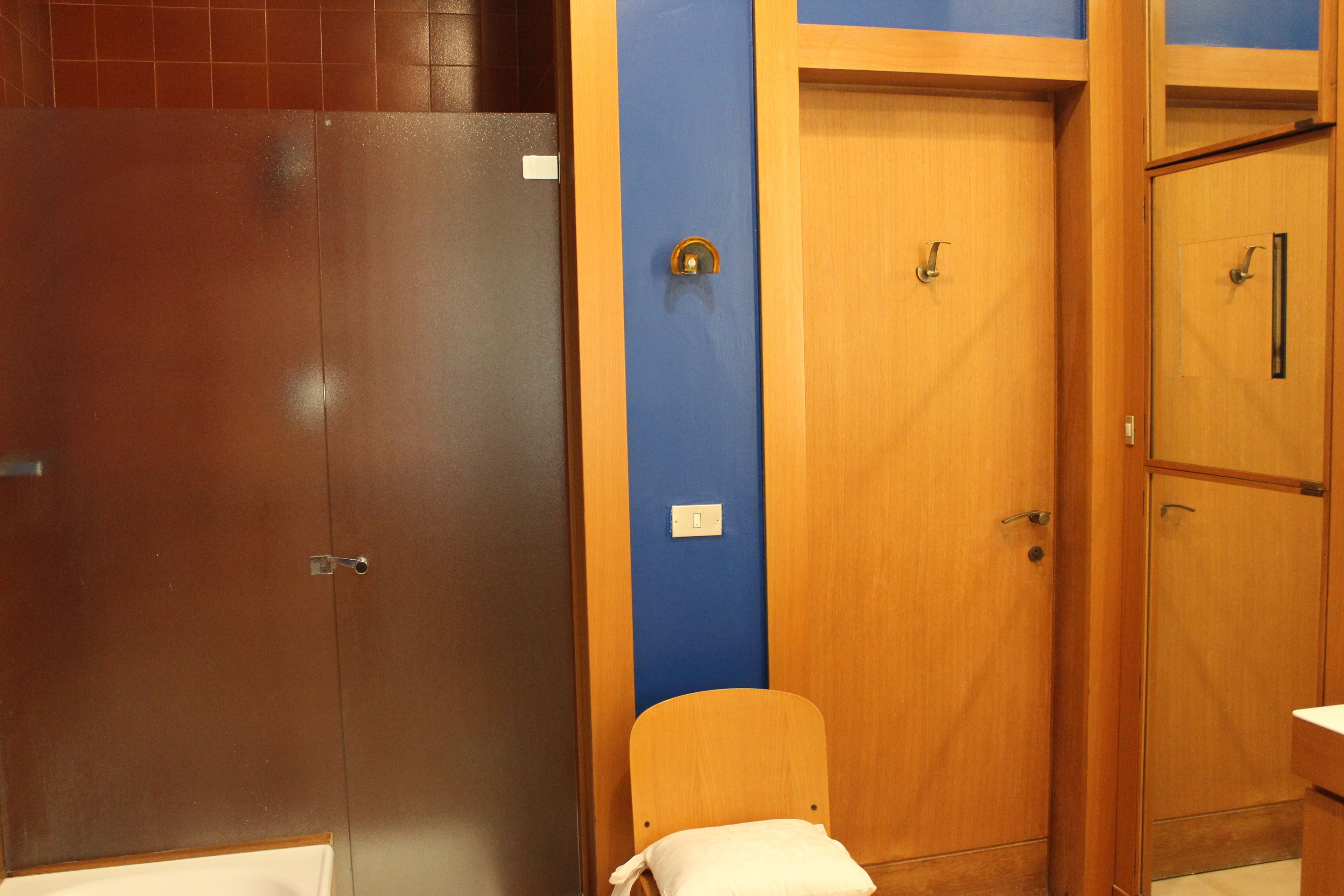 Un bagno con porte in legno, una parete blu e una sedia di legno con un asciugamano bianco.