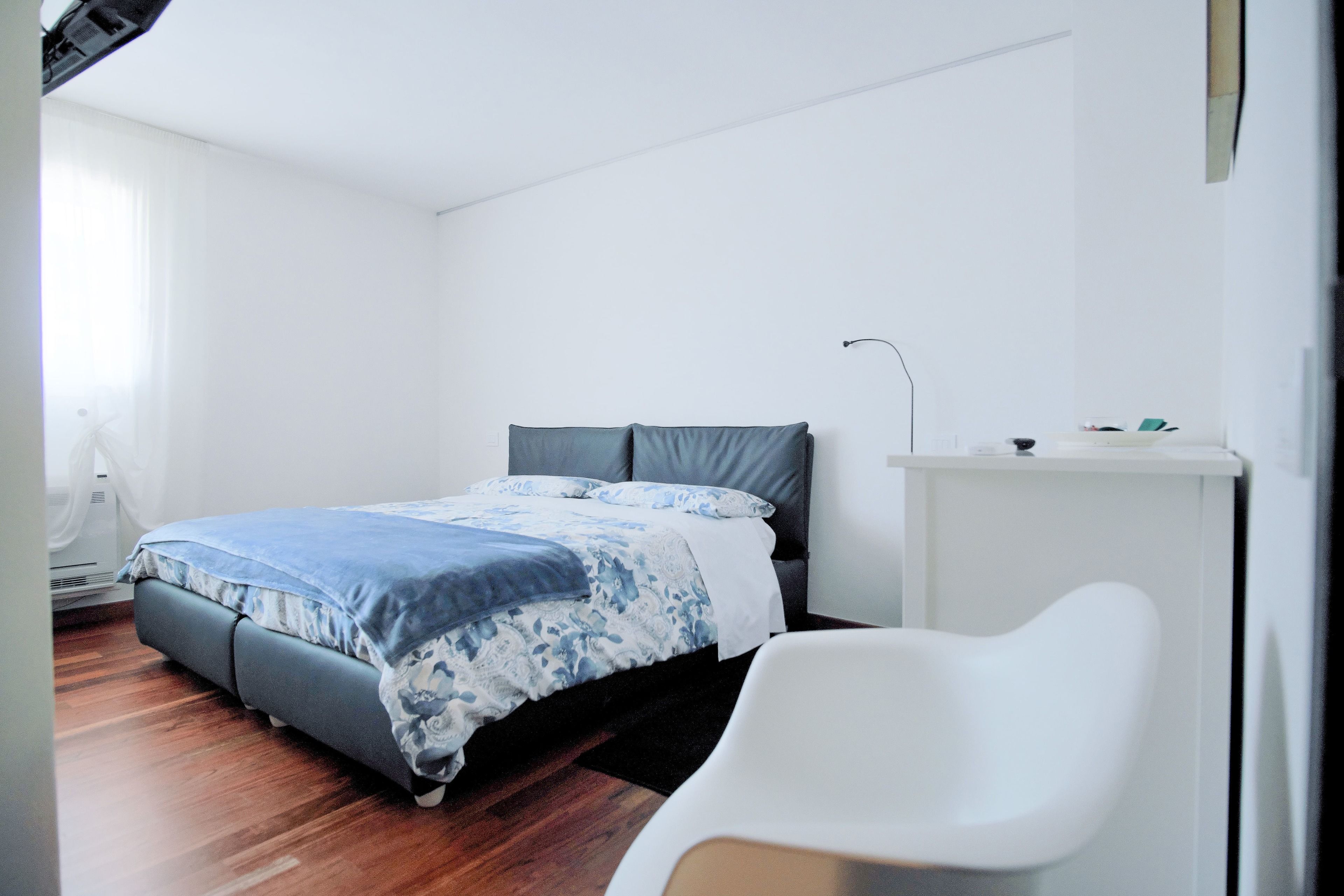 Un dormitorio con cama, una silla y un escritorio.