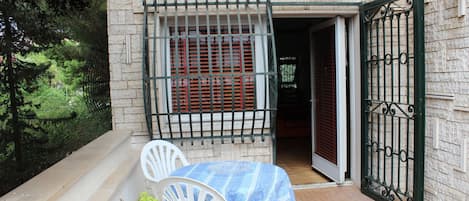 A patio area with a table and chairs, a small plant, and a door with a metal gate.
