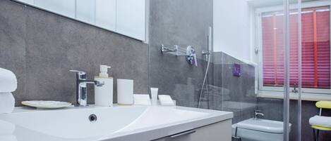 Et moderne badeværelse med et stort, hvidt badekar, en glasafskærmet brusekabine og et lille toilet.