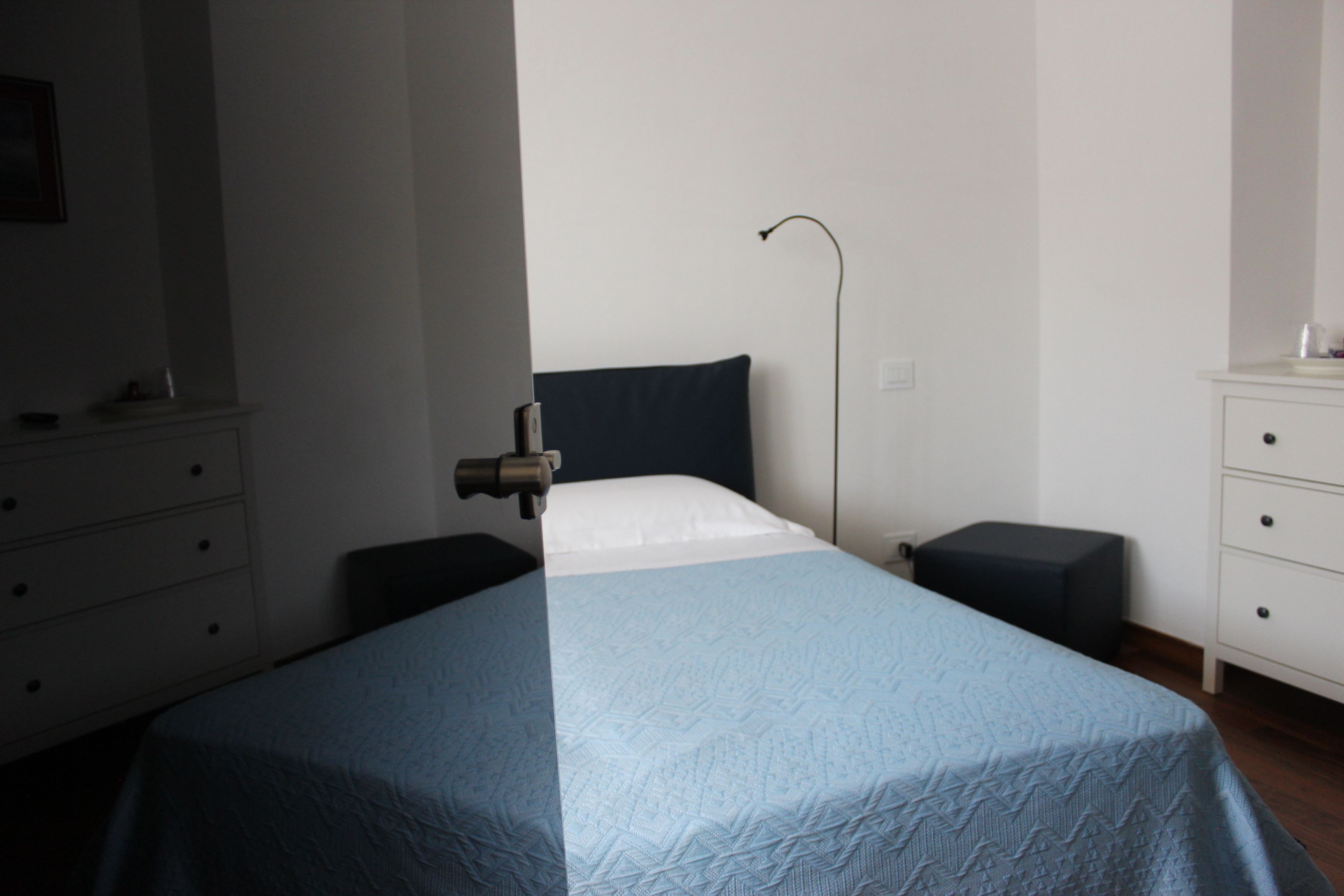 A bedroom with a bed, bedside tables, a dresser, and a lamp.