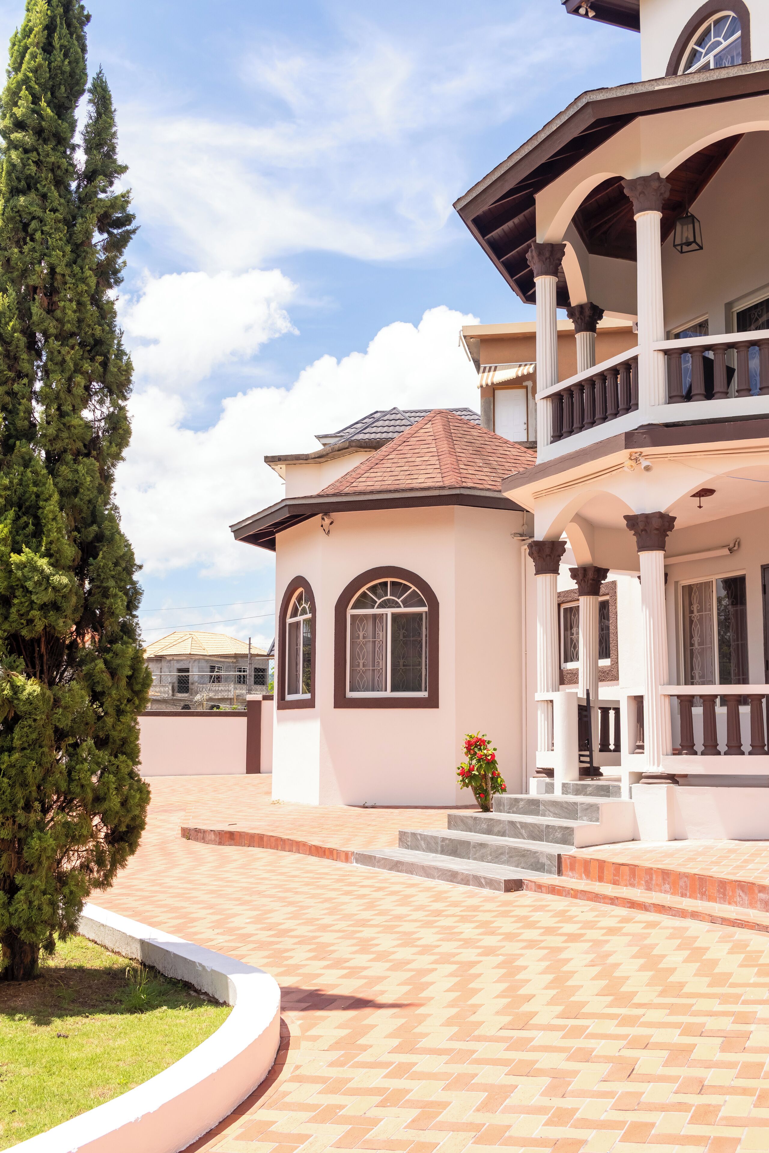 Una casa a due piani con un balcone, un portico coperto e un vialetto in mattoni che conduce all'ingresso.