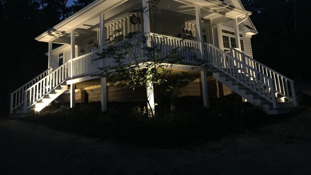 A two-story house with a covered porch and a staircase leading to the upper level. - Stonehill Cottages (Mena)