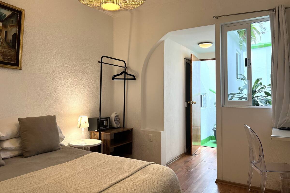 A bedroom with a bed, bedside table, lamp, and a hanging light fixture.