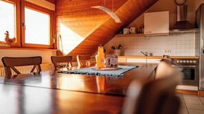 Un intérieur en bois comprenant un coin cuisine, une table à manger avec des chaises et une bouteille de jus.