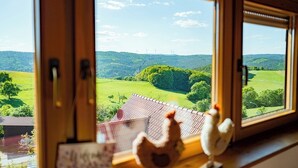 Een uitzicht op een groen landschap en windmolens vanuit een raam.