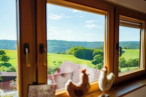 A window with a view of a green landscape and wind turbines. - Vacation apartment with a view of the countryside - ideal for families and friends up to 6 pers. (Rothenberg)
